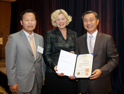 Consul General Jeong Gwan Lee (left) and Consul Kwang Ho Lee (right) of the Korean Consulate General in San Francisco present the Korean Presidential Citation to Susanne Stirling.