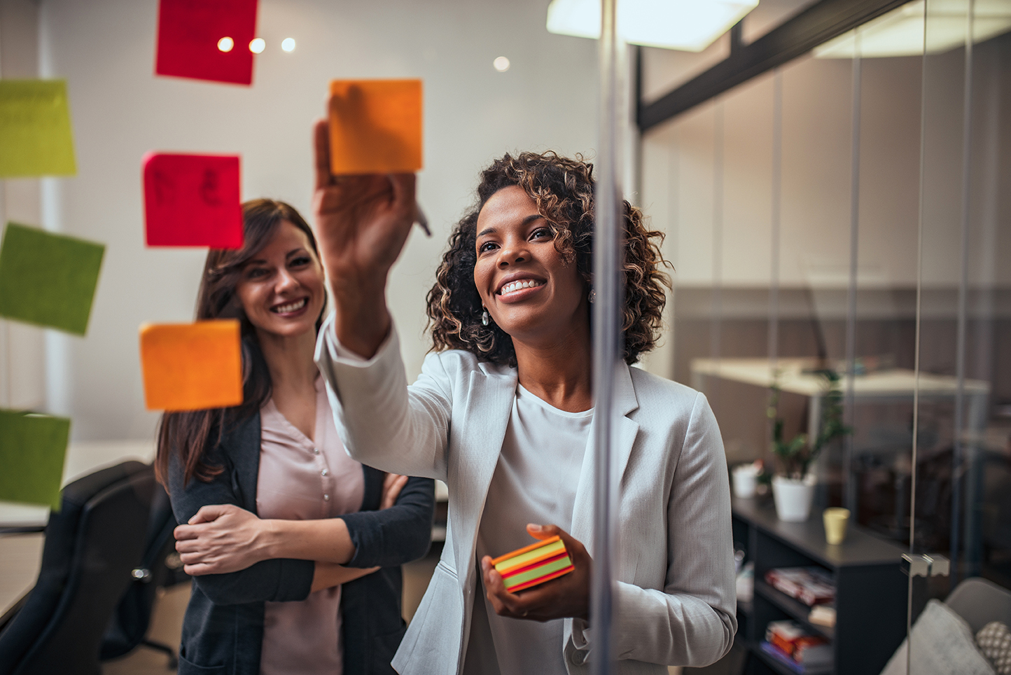 Creative businesswoman writing on sticky notes on a glass wall,