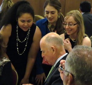  Gov. Brown signs trade mission briefing book for delegation support staff. (Left to Right) Valeria Sanabia, Deidre Graham and Mary Douglass